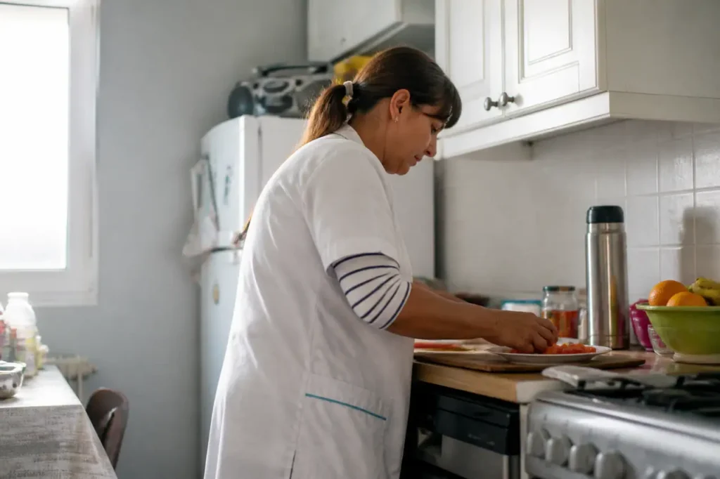 Aide a domicile preparant le repas dans cuisine lumineuse