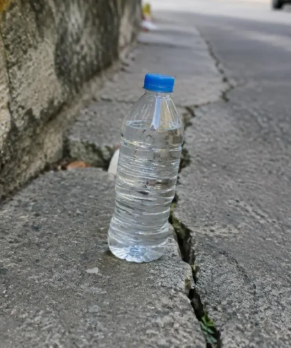 Bouteille en plastique posee sur un trottoir fissure
