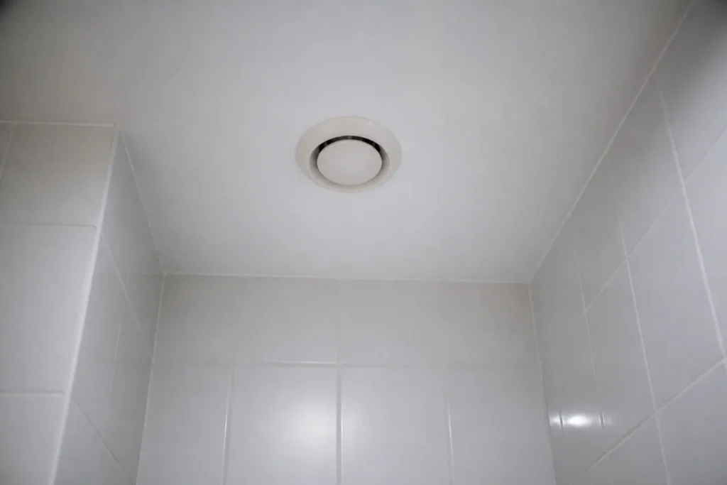 Grille blanche ronde fixee au plafond, carrelage blanc autour
