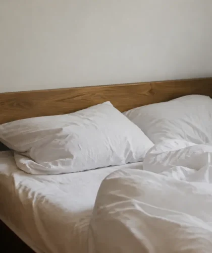 Lit en bois contre le mur avec draps blancs