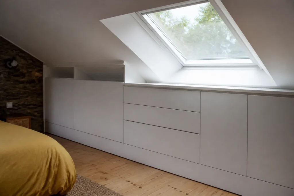 Meuble blanc sur mesure contre un toit incline fenetre