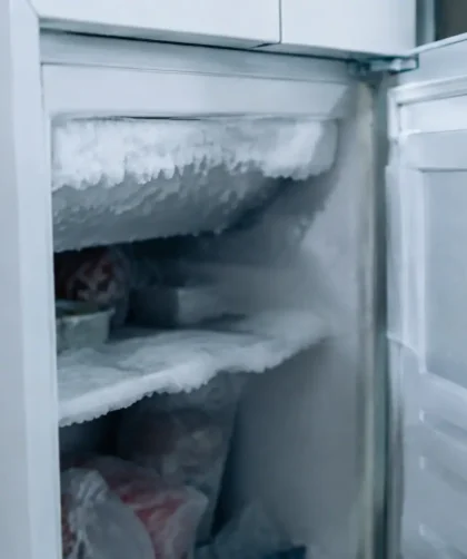 Porte entrouverte laissant voir du givre sur appareil blanc