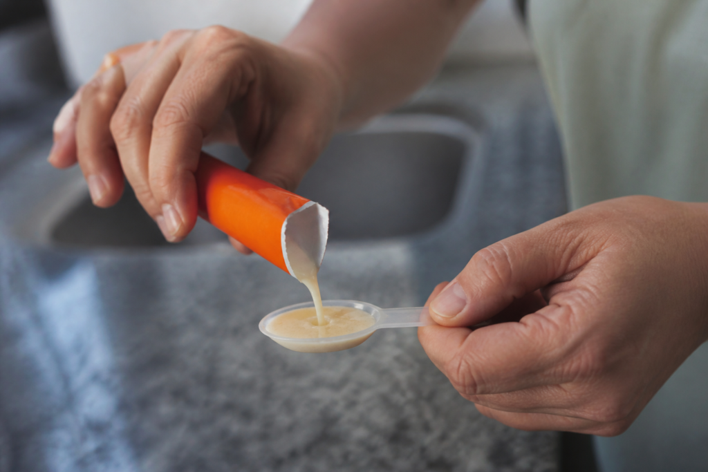 Sachet ouvert versant suspension liquide dans cuillere doseur