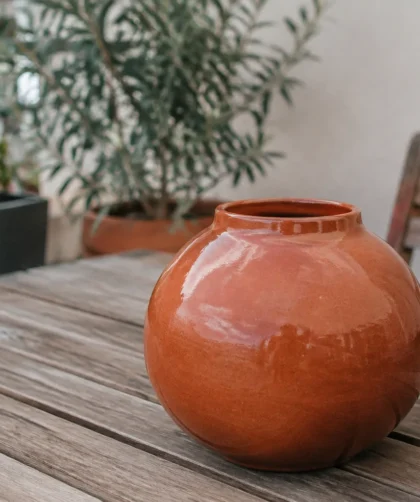 Vase rond orange brique posé sur une terrasse