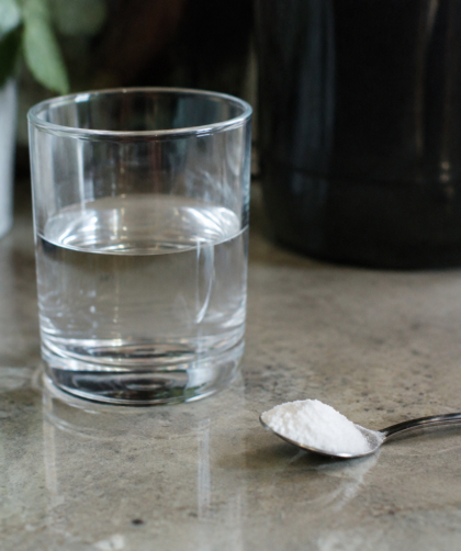 Verre d'eau et cuillère de poudre blanche sur comptoir