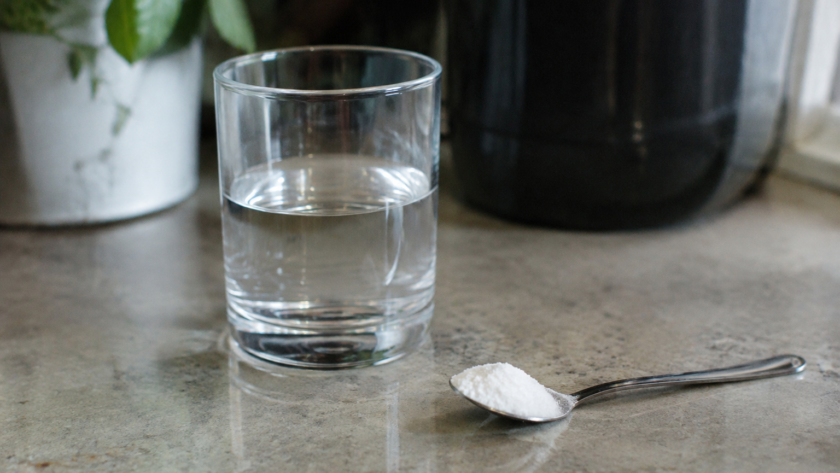 Verre d'eau et cuillère de poudre blanche sur comptoir